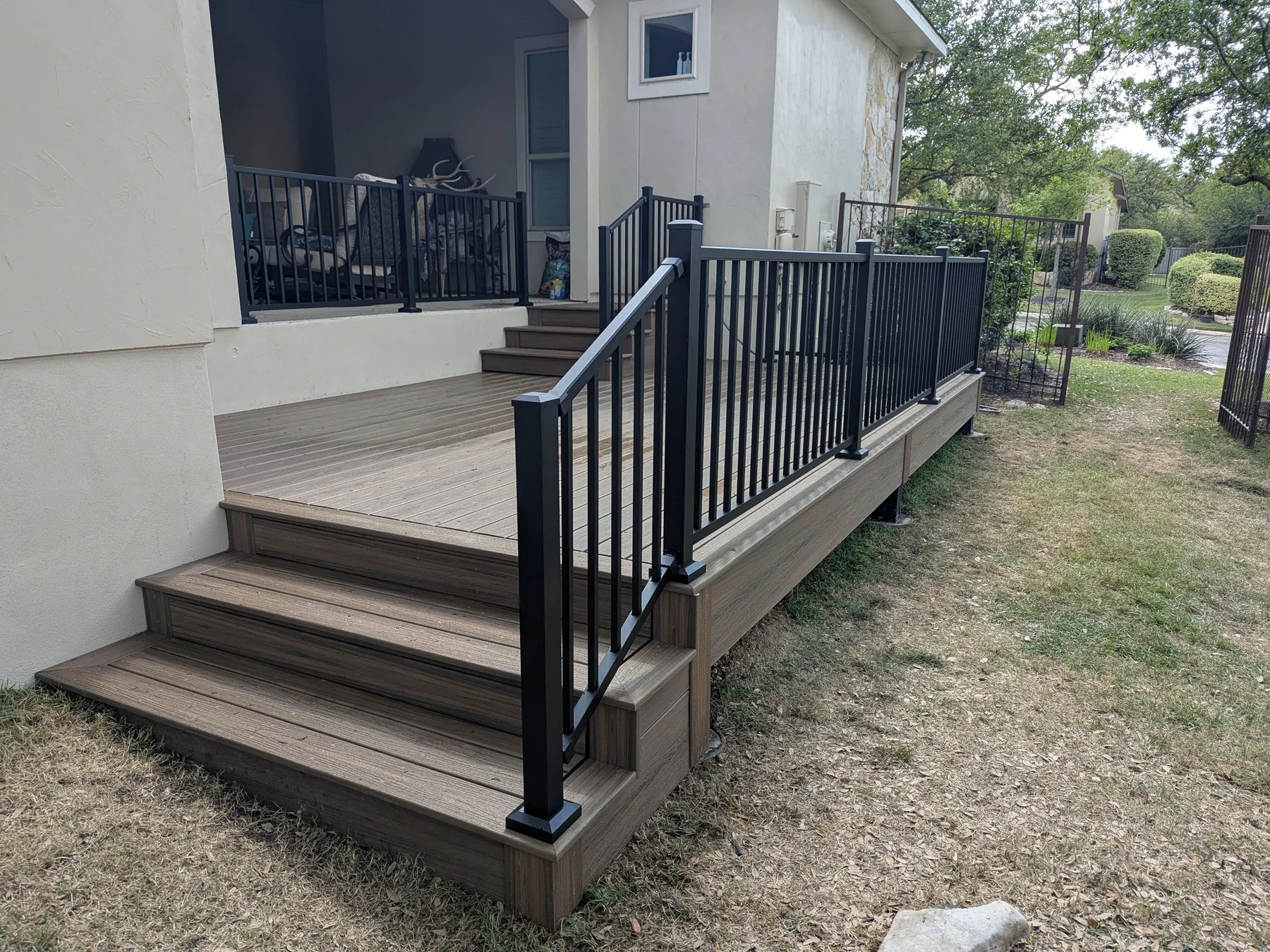 Finished Trex deck with black metal railings and easy-tread steps