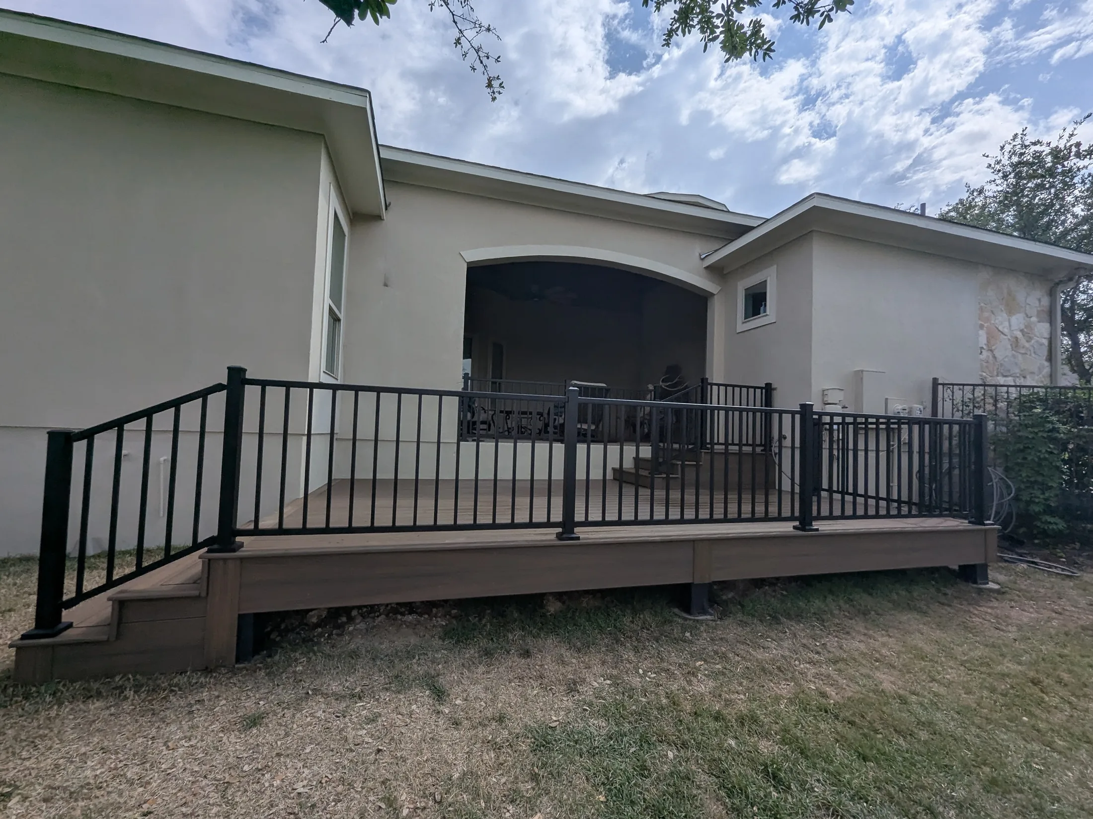 Finished Trex deck with black metal railings and easy-tread steps in Scenic Oaks