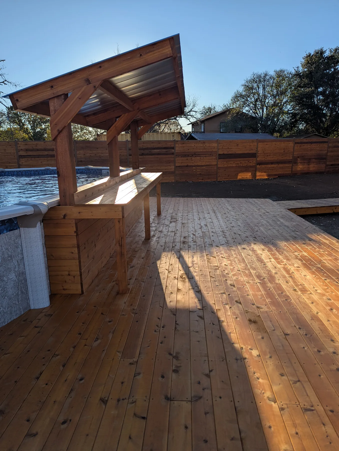 Covered cedar bar area built beside the above-ground pool deck