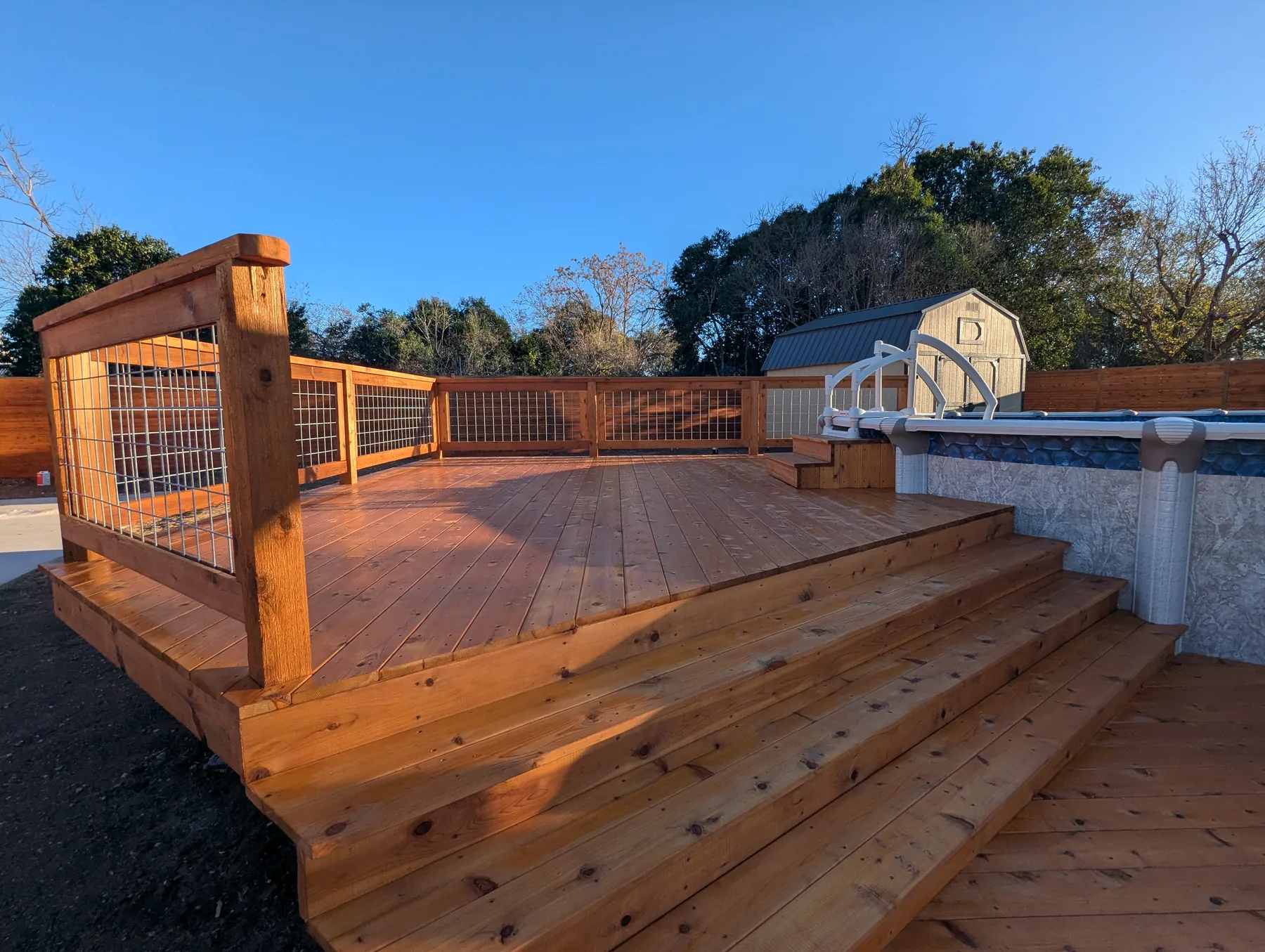 Wide cedar stairs leading from the lower pool deck to the upper pool access level