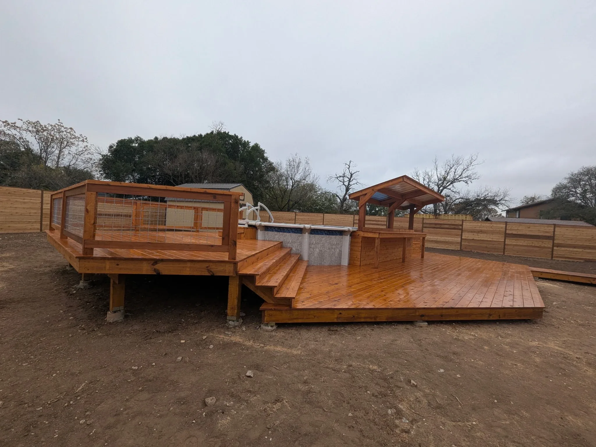 Finished two-tier cedar pool deck around oval above-ground pool