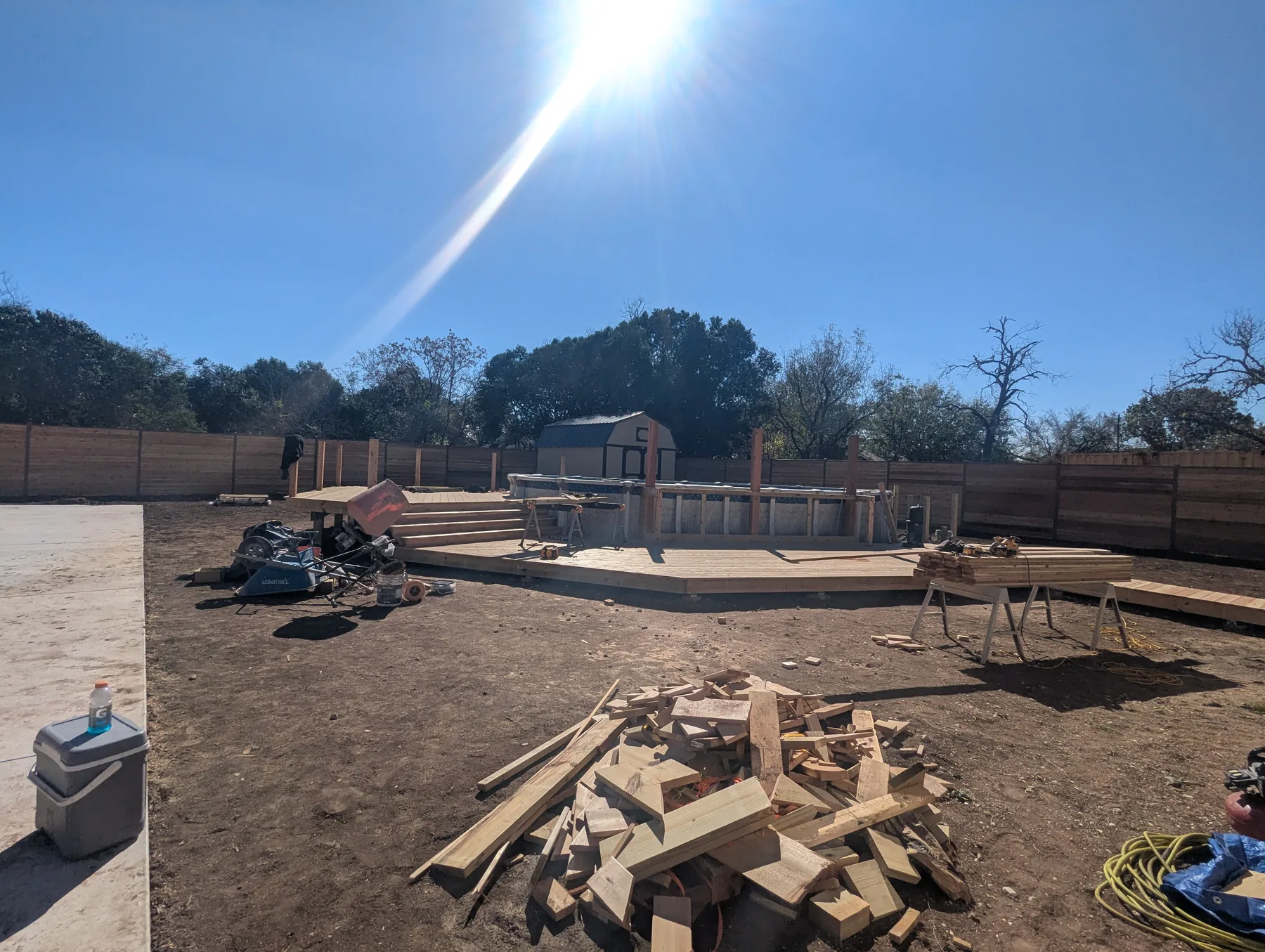 Two-tier cedar pool deck under construction around an above-ground oval pool