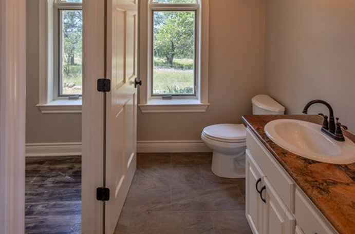 New tile floors and vanity quartz countertop for a bathroom remodel in the Hill Country.